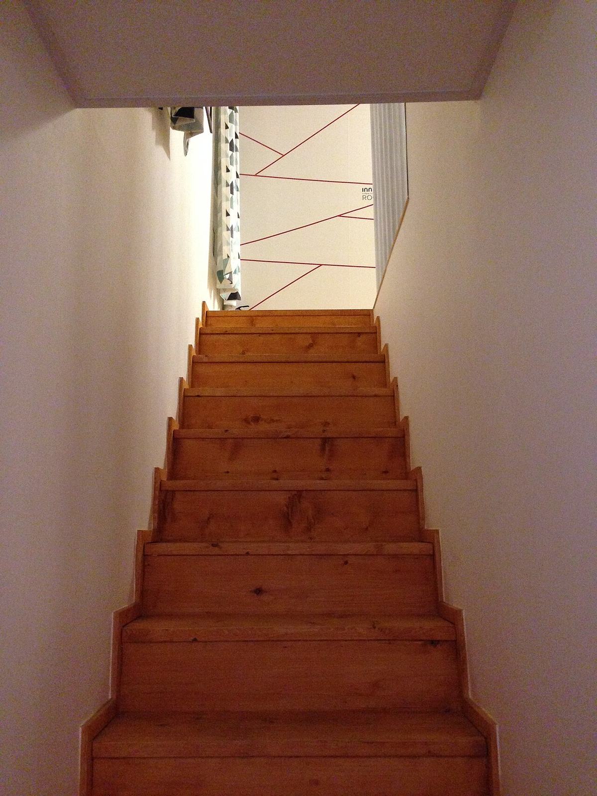 Escalier droit en bois entre deux murs blancs